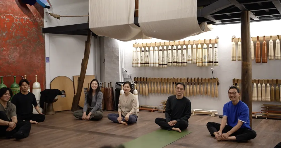 방망이가 걸린 벽 앞 마룻바닥에 여섯 명이 책상다리로 앉아 웃고 있다