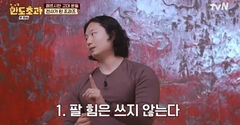 붉은 벽 앞에서 긴 머리 사람이 손가락을 세워 설명하고, 자막은 「1. 팔 힘은 쓰지 않는다」