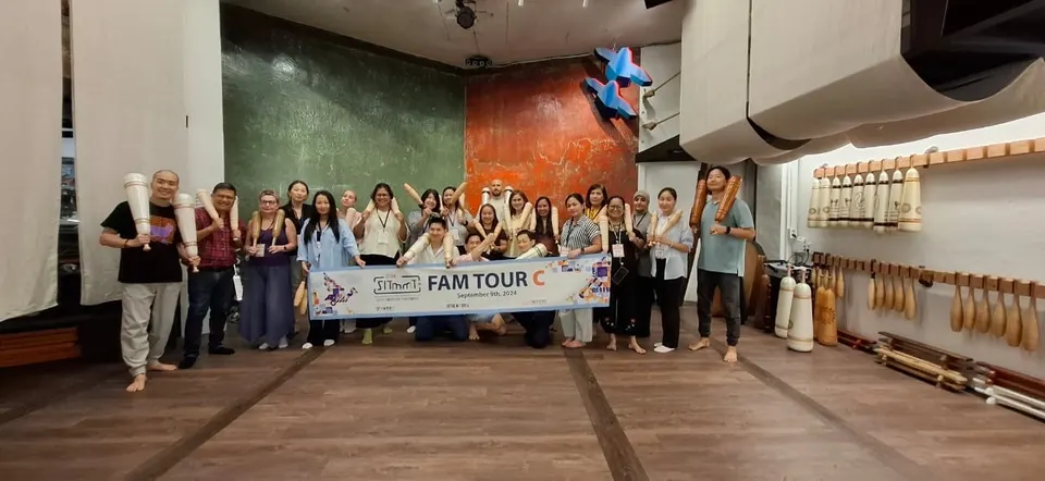 「FAM TOUR C」 현수막을 든 스무 명 남짓이 방망이가 걸린 운동실에 모여 방망이를 들고 섰다