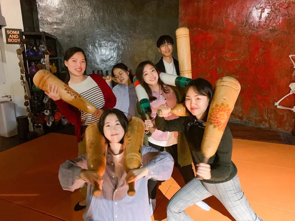 주황 바닥의 운동실에서 여섯 명이 나무 페르시안밀을 하나씩 들고 저마다 자세를 잡았다