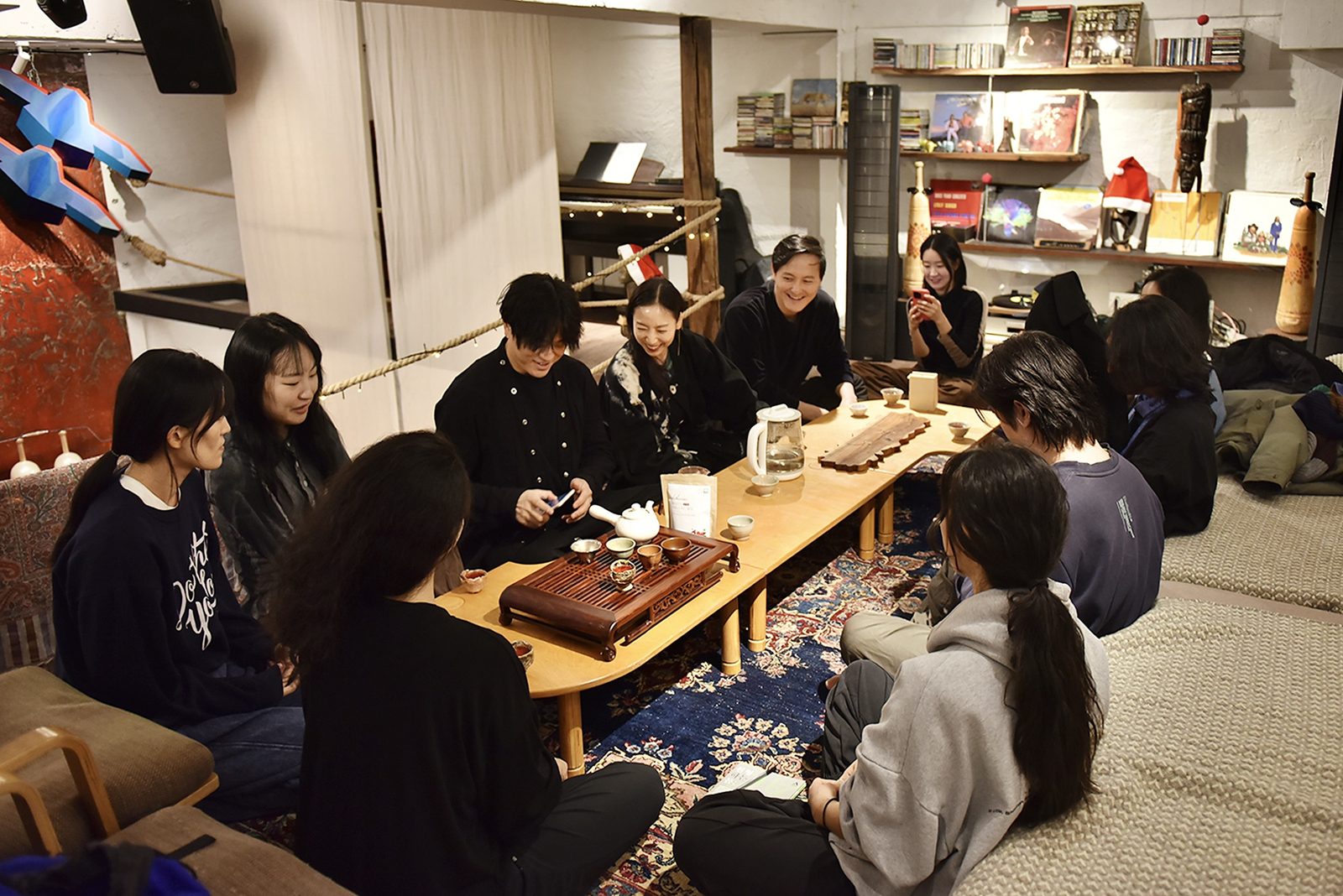 운동을 마친 사람들이 낮은 탁자에 둘러앉아 차를 마시며 이야기하고 있다