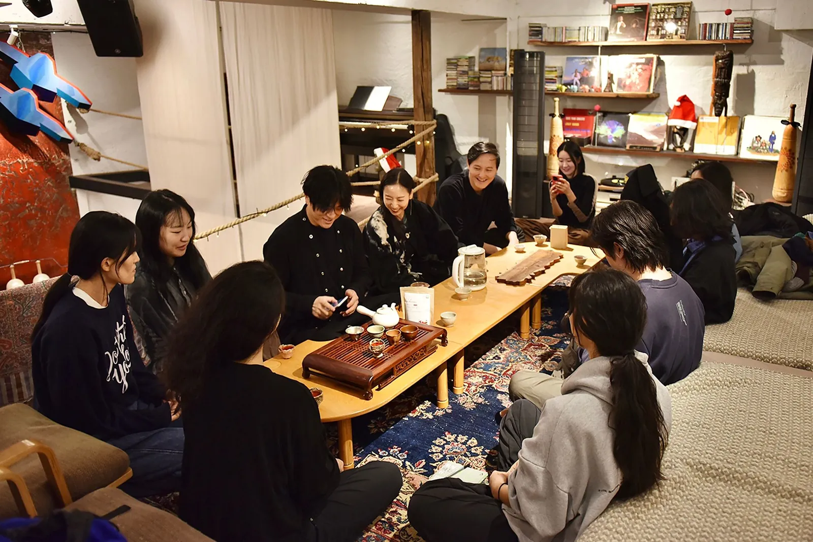 긴 찻상에 둘러앉아 함께 웃는 사람들